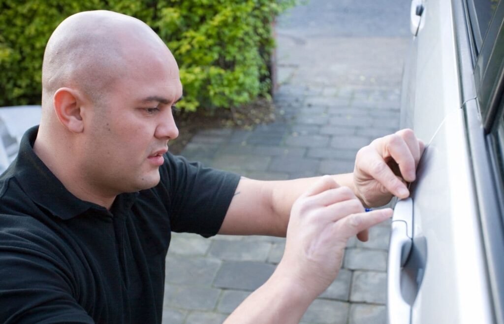 Técnico especializado en cerrajería automotriz abriendo la puerta de un automóvil de manera segura y profesional.