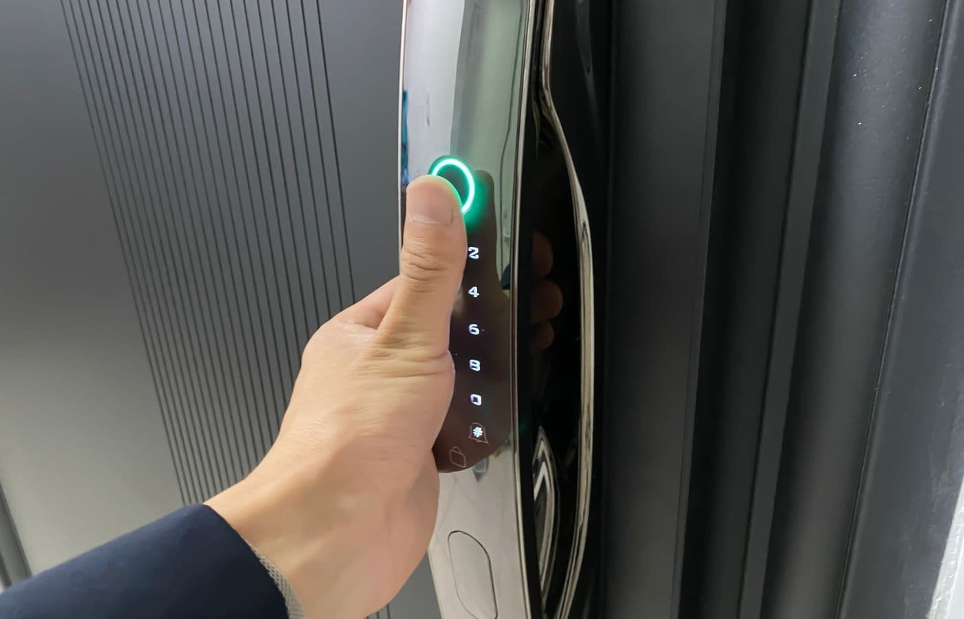 Persona desbloqueando una puerta con una cerradura biométrica de huella digital, mostrando tecnología de seguridad avanzada para hogares y negocios.