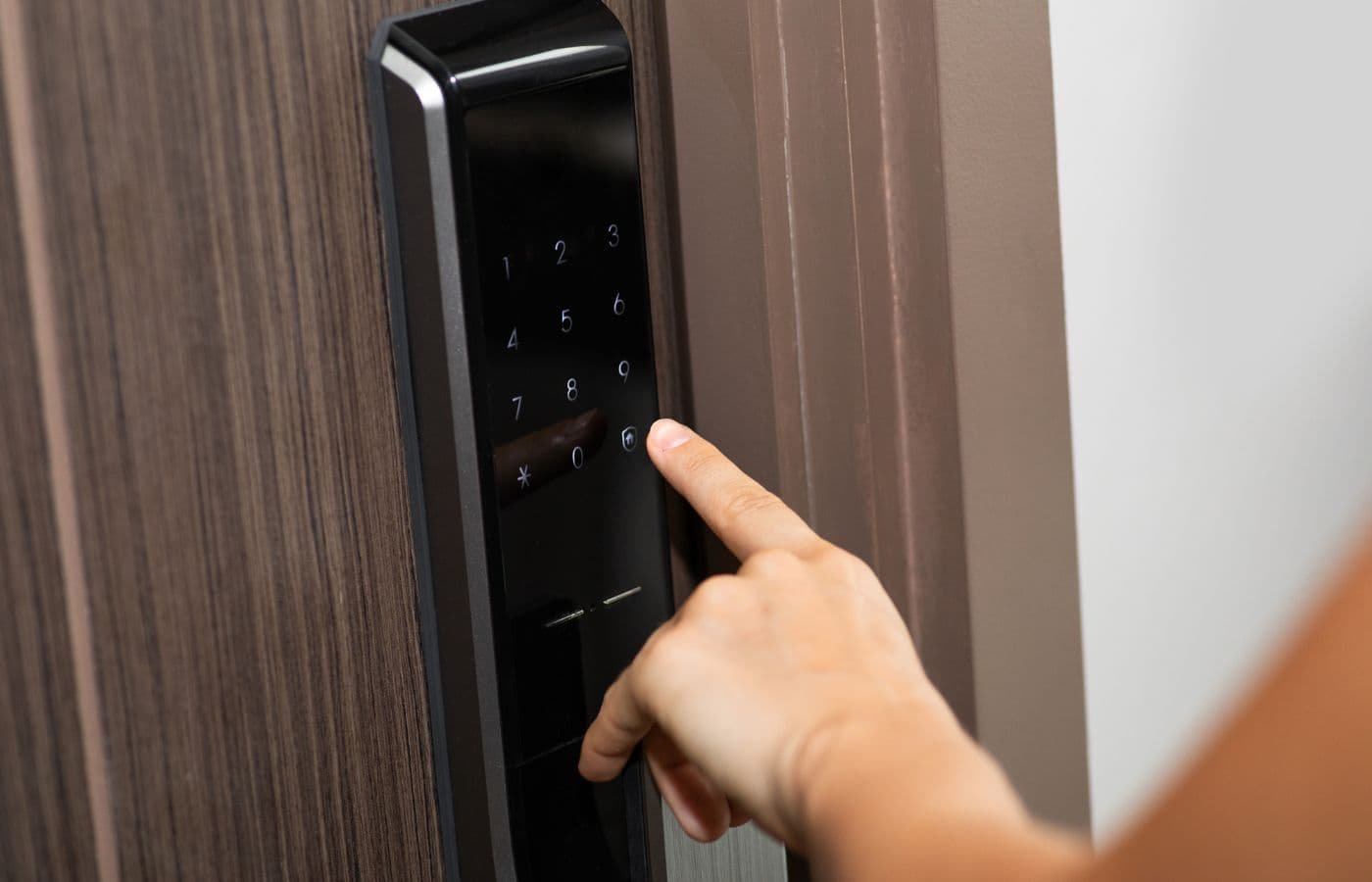 Persona ingresando código en una chapa electrónica para puerta instalada en entrada residencial.